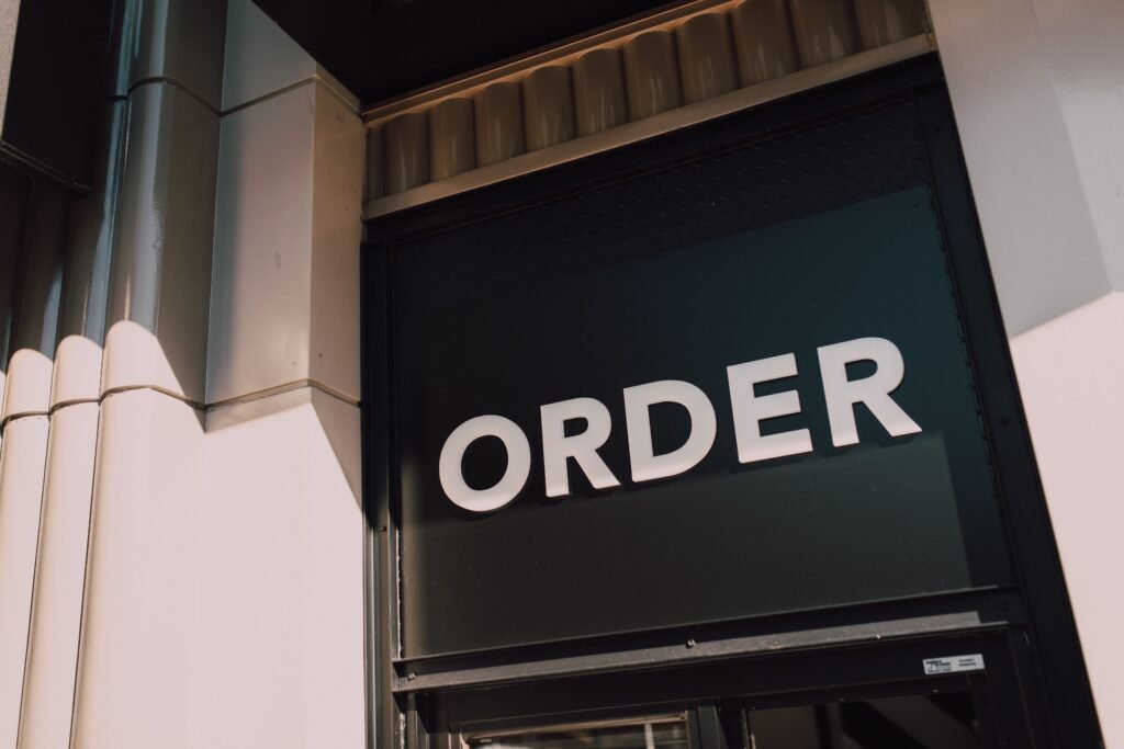 pexels-photo-6413702-6413702 A sunlit view of a modern storefront with prominent 'Order' signage, highlighting a streamlined design.